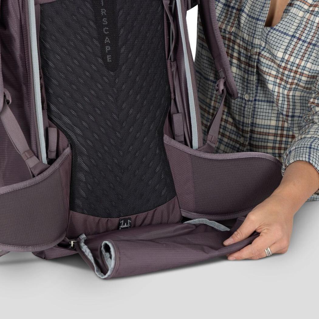 A woman shows the bottom compartment of the Osprey Fairview 40 backpack in black against a white background.