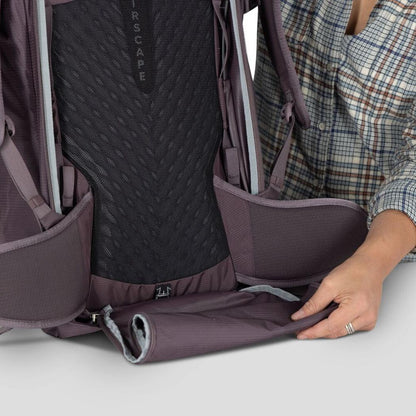 A woman shows the bottom compartment of the Osprey Fairview 40 backpack in black against a white background.