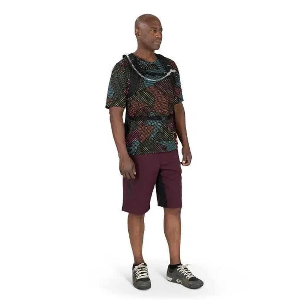 A man wearing the Osprey Katari 7 hydration pack stands in a side view against a white background.