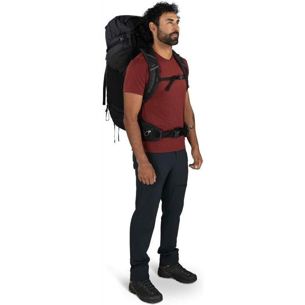 A man wearing the Osprey Kestrel LT 65 backpack stands in a side view against a white background.