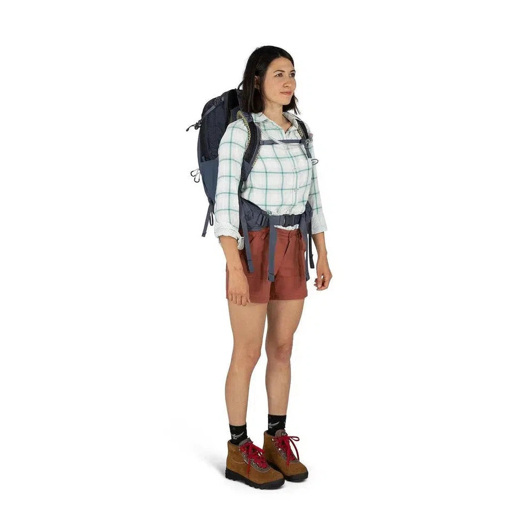 A woman wearing the Osprey Mira 32 in Anchor Blue stands against a white background.