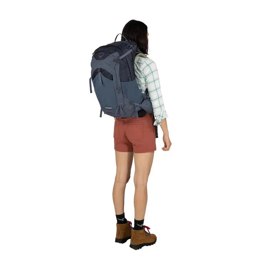 Back view of the Osprey Mira 32 in Anchor Blue showing the large main compartment and a model wearing it against a white background.