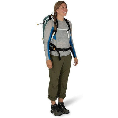 A woman wearing the Osprey Sirrus 24 backpack in Medium Grey stands against a white background.