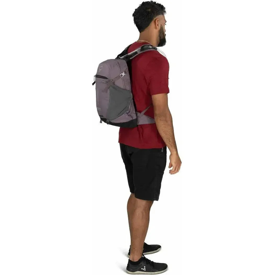 Side view of the Osprey Sportlite 15 Hydraulics backpack in Graphite Purple on a model against a white background.