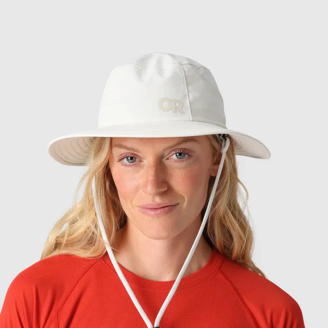 A woman wears the Outdoor Research Helios Sun Hat in Light Pewter against a plain white background.