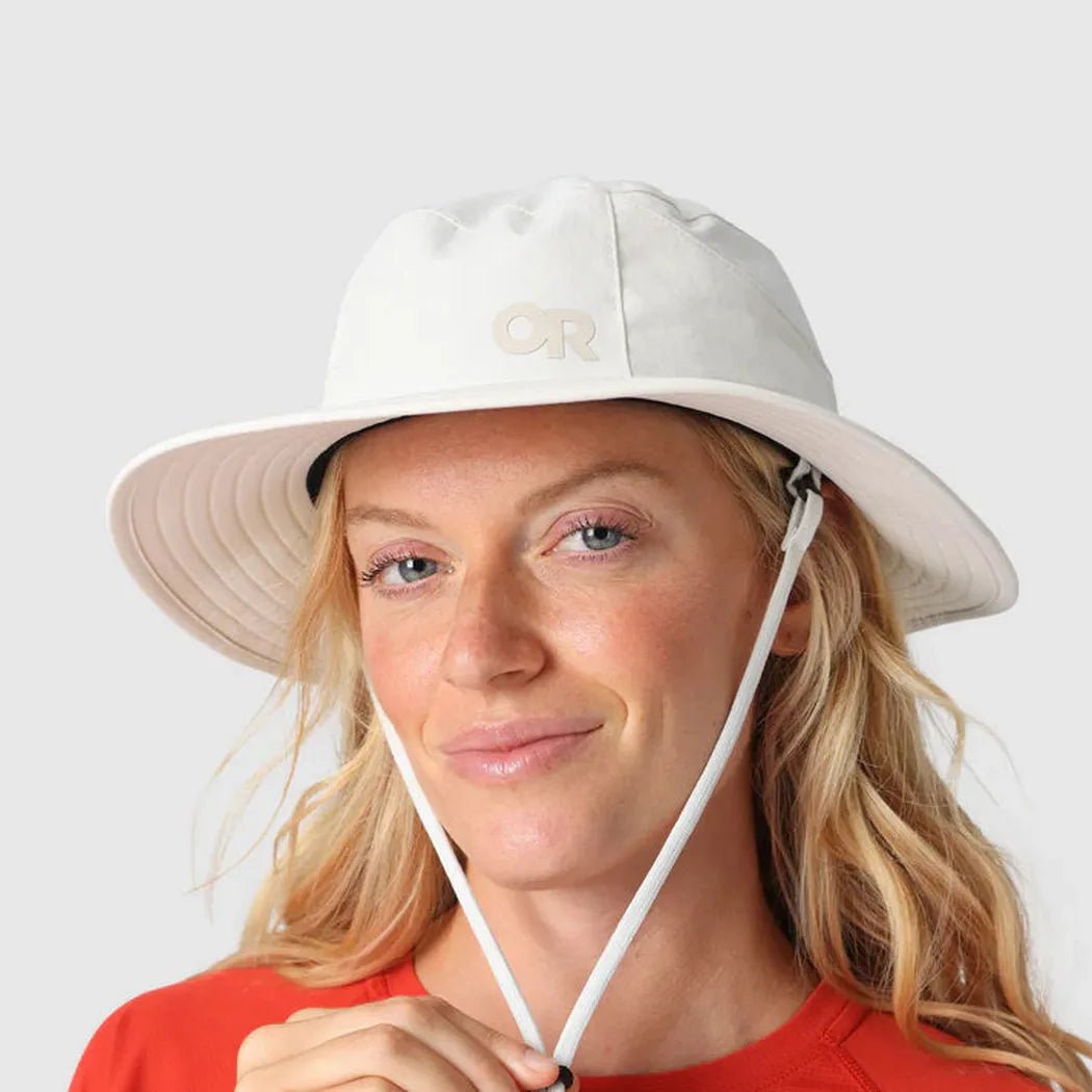 A woman wears the Outdoor Research Helios Sun Hat in Light Pewter against a plain white background.