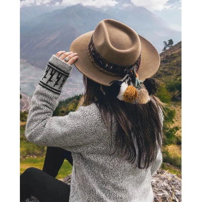 A woman in a light grey Paka Apparel The Costa hat sits outdoors with mountains in the background.