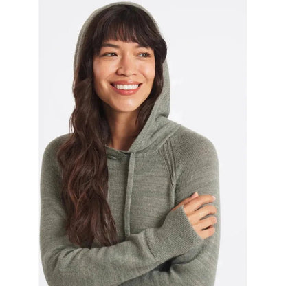 A woman wearing the Paka Apparel Women's Hoodie in Willow stands with her arms crossed against a plain white background.