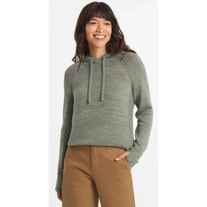 A woman wearing the Paka Apparel Women's Hoodie in Willow stands against a plain white background with one hand in her pocket.