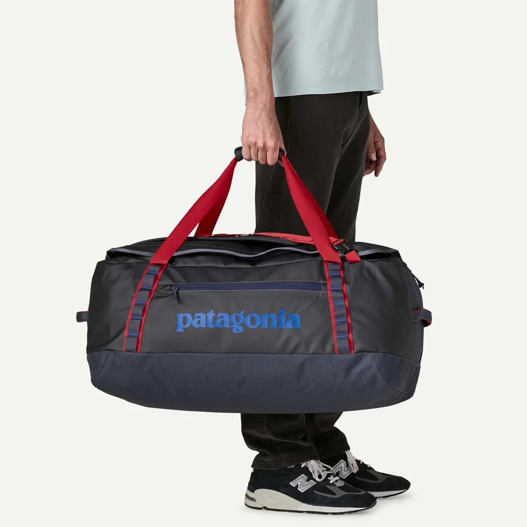 A person holding a Patagonia Black Hole Duffel 70L in Black w/ Black against a white background.