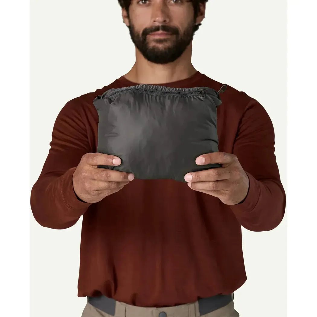 A man wearing a Marlow Brown Patagonia Men's Nano Puff Jkt holds the jacket in front of him against a plain white background.