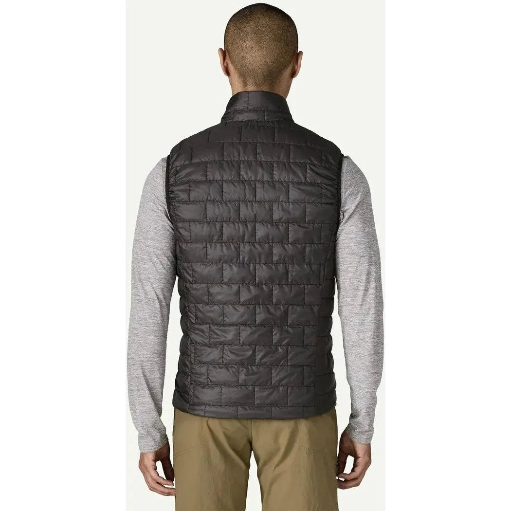 Back view of the Patagonia Men's Nano Puff Vest in Black on a model wearing khaki pants against a white background.