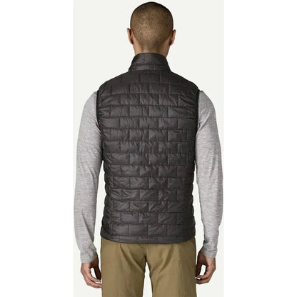 Back view of the Patagonia Men's Nano Puff Vest in Black on a model wearing khaki pants against a white background.