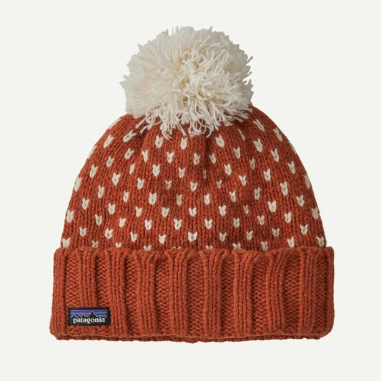 A front view of the Patagonia Snowbelle Beanie in Burnished Red with a white pom pom and ribbed cuff, displayed against a plain white background.