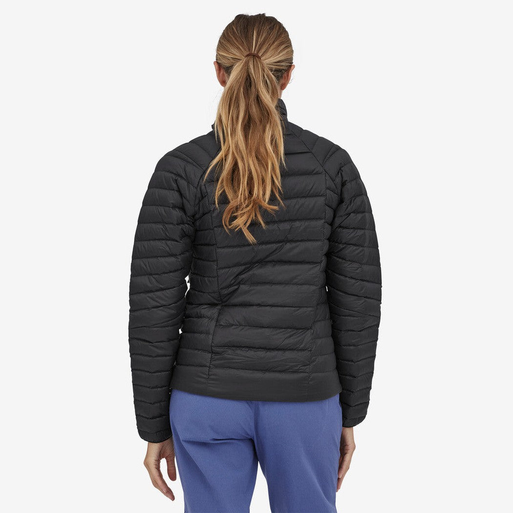 Back view of the Patagonia Women's Down Sweater in Black on a model wearing blue pants against a white background.