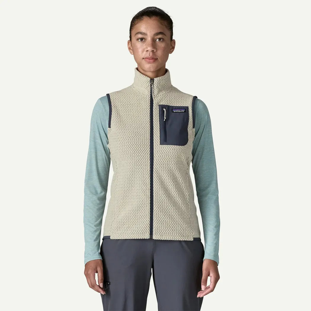 A front view of the Patagonia Women's R1 Air Vest in Wool White on a model wearing light blue long sleeves and dark pants against a plain white background.