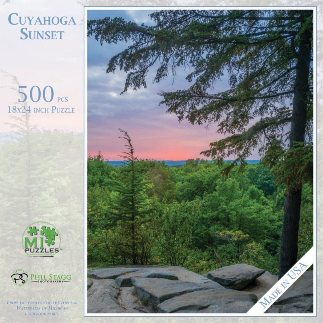 A 500 piece Cuyahoga Sunset puzzle by Phil Stagg Photography shows a sunset over a forest with rocks in the foreground.