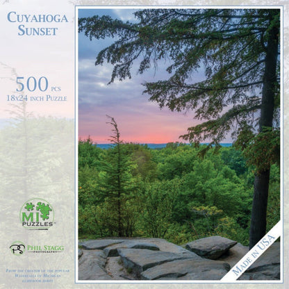 A 500 piece Cuyahoga Sunset puzzle by Phil Stagg Photography shows a sunset over a forest with rocks in the foreground.