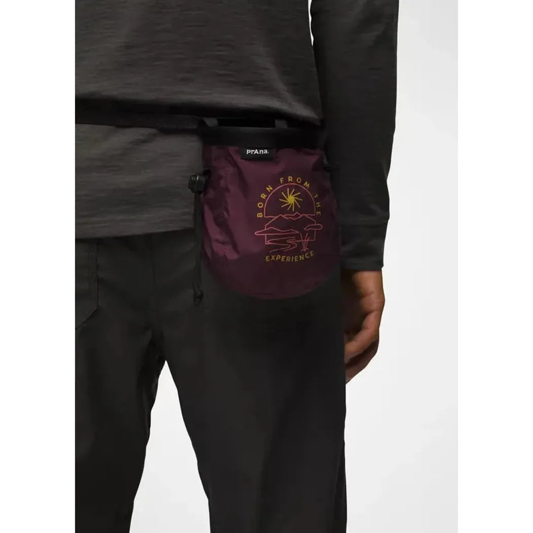 Side view of the Prana Graphic Chalk Bag in Black Bloom on a model wearing black pants against a white background.