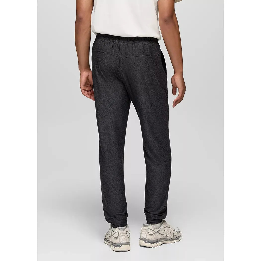 Back view of the Prana Men's Altitude Tracker LT Jogger in Black Heather on a model wearing white sneakers against a light gray background.
