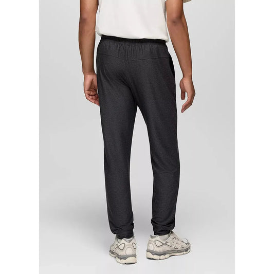 Back view of the Prana Men's Altitude Tracker LT Jogger in Black Heather on a model wearing white sneakers against a light gray background.