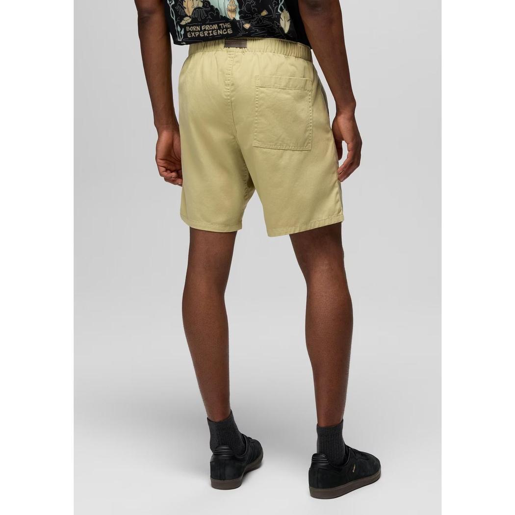 Back view of the Prana Sample - Men's Durado Short in Jackfruit showing the back pocket and elastic waistband on a model wearing black shoes against a light gray background.