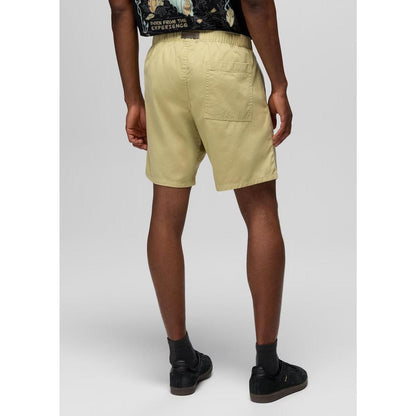 Back view of the Prana Sample - Men's Durado Short in Jackfruit showing the back pocket and elastic waistband on a model wearing black shoes against a light gray background.
