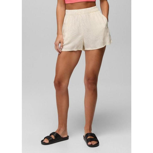 A front view of the Prana Sample - Women's The Bahamas Short in BeachPebbleShor on a model wearing black slides against a gray background.