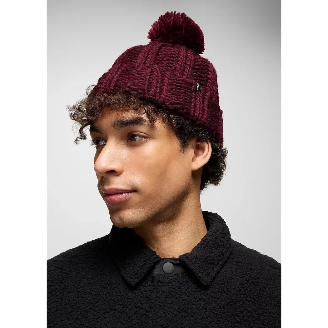 Side view of the Prana Snow Crystal Beanie in Deep Vino on a model wearing a black jacket against a light gray background.