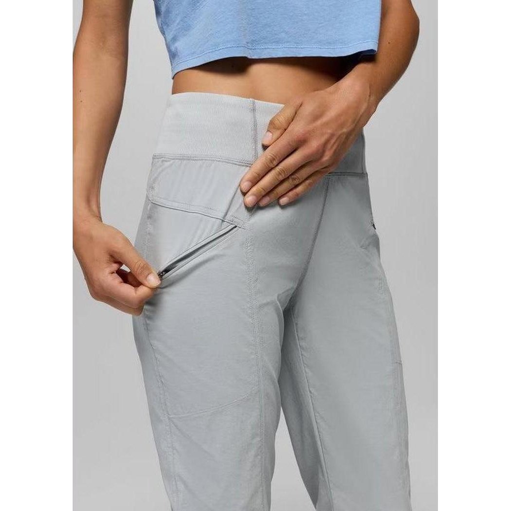 A model wearing the grey blue Prana Women's Koen Mid Rise Daily Pant shows the zippered pocket detail.