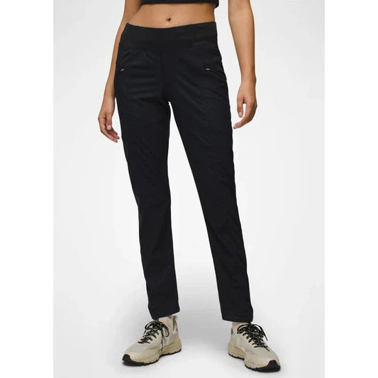 A front view of the Prana Women's Koen Pant in Black on a model wearing light-colored hiking shoes against a plain white background.