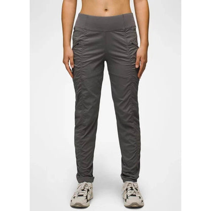 A front view of the Prana Women's Koen Pant in Black, showing the high waist and cargo pockets on a model wearing white sneakers against a plain background.
