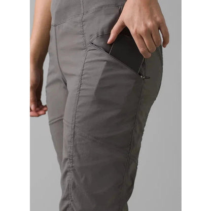 Side view of the Prana Women's Koen Pant in Black showing the front pocket with a phone inside against a light gray background.