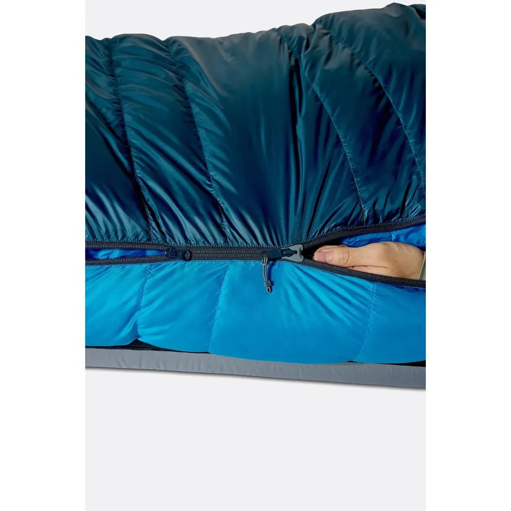 A close-up of the Rab Ascent -6C / 20F - Left Zip sleeping bag in Tempest Blue/Maya Blue showing the left zip and a hand pulling it closed.