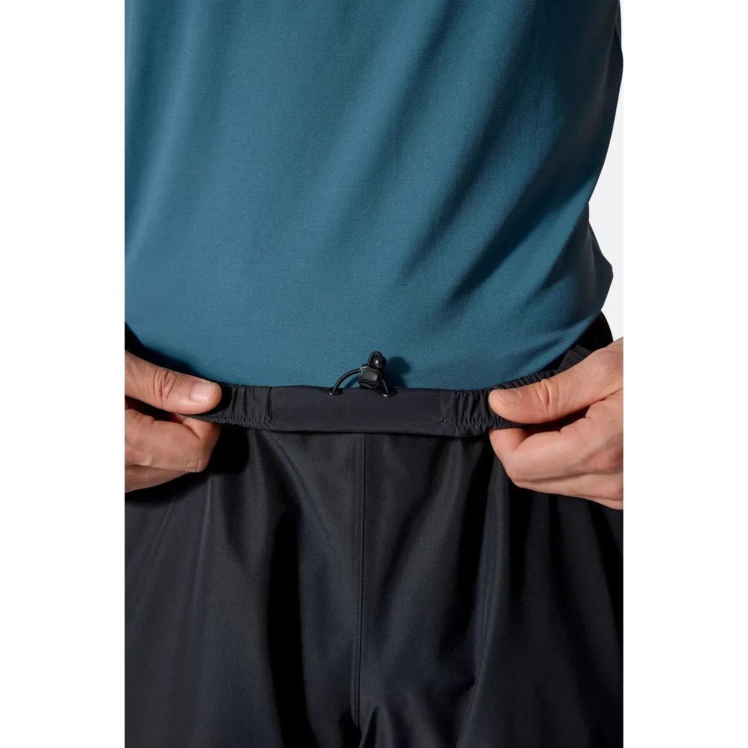 A close-up of a model wearing Rab Men's Downpour Pants in Black, showing the waistband and drawcord against a white background.