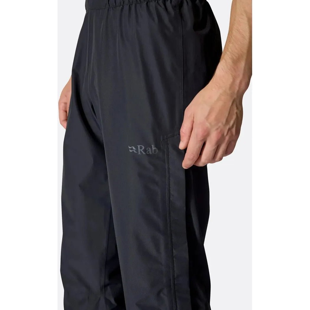 Side view of the Rab Men's Downpour Pants in Black showing the elastic waistband and the Rab logo on the leg.