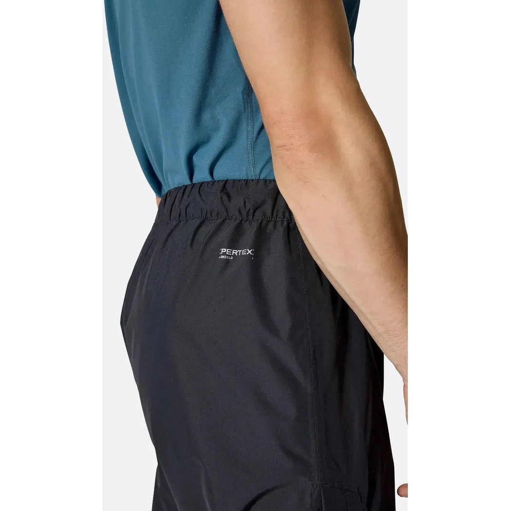 Side view of the Rab Men's Downpour Pants in Black showing the elastic waistband and model wearing them against a white background.