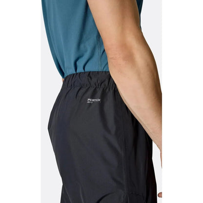 Side view of the Rab Men's Downpour Pants in Black showing the elastic waistband and model wearing them against a white background.