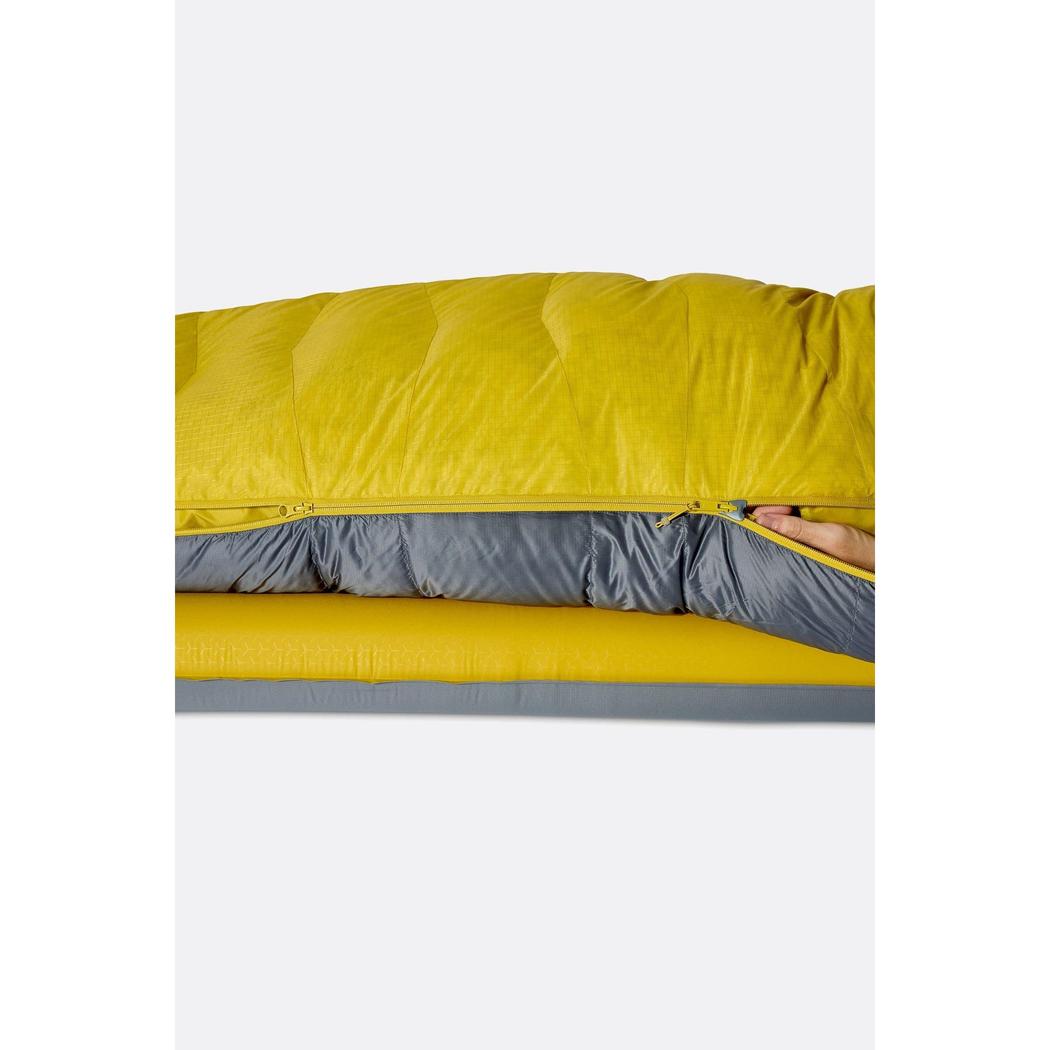 A side view of the Rab Neutrino 0C / 32F Graphene/Dark Pollen sleeping bag showing the zipper and a hand reaching in against a white background.