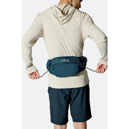Back view of the Rab Protium 6 in Anthracite on a model wearing a light hoodie and dark shorts against a plain white background.