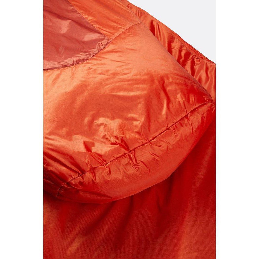 A close-up of the Rab Solar Eco 1 sleeping bag in Red Clay, showing the quilted synthetic insulation and smooth outer shell against a light background.