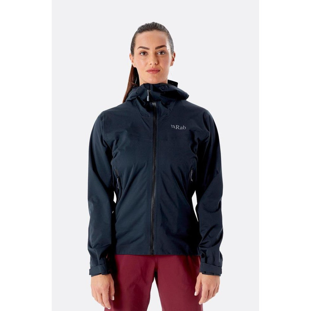 A front view of the Rab Women's Kinetic 2.0 Jacket in Ultramarine on a model wearing maroon pants against a plain white background.