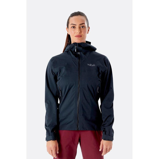 A front view of the Rab Women's Kinetic 2.0 Jacket in Ultramarine on a model wearing maroon pants against a plain white background.