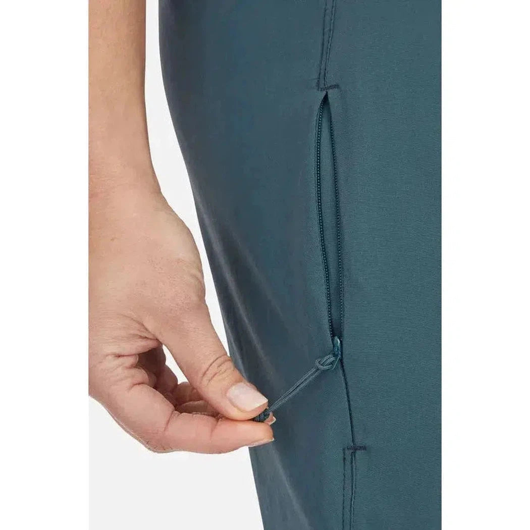 A close-up of the Rab Women's Momentum Pants in Beluga showing the zippered pocket and a hand interacting with it.
