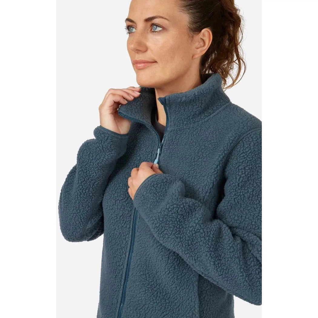 A woman wearing the Rab Women's Shearling Jacket in Orion Blue, shown from the side with a high collar and zipper, against a plain white background.