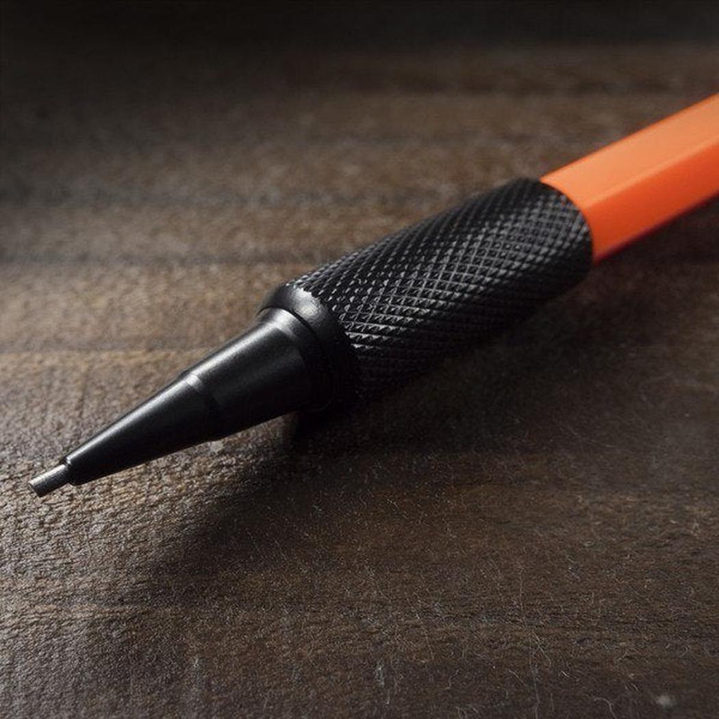 A close-up of the Rite in the Rain 1.3mm Mechanical Clicker Pencil with its black textured grip and orange body resting on a dark wooden surface.