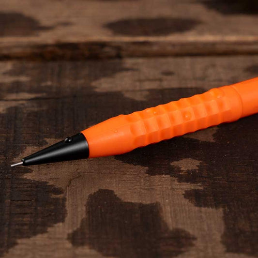 A close-up of the Rite in the Rain Precision TWIST Pencil - 0.9MM in Orange lying on a dark wooden surface.