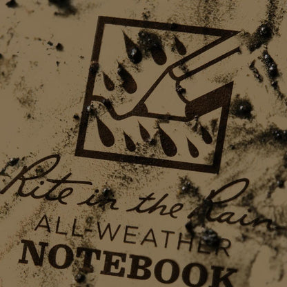 A close up of the Rite in the Rain notebook showing the all weather logo and text on a dirty background.