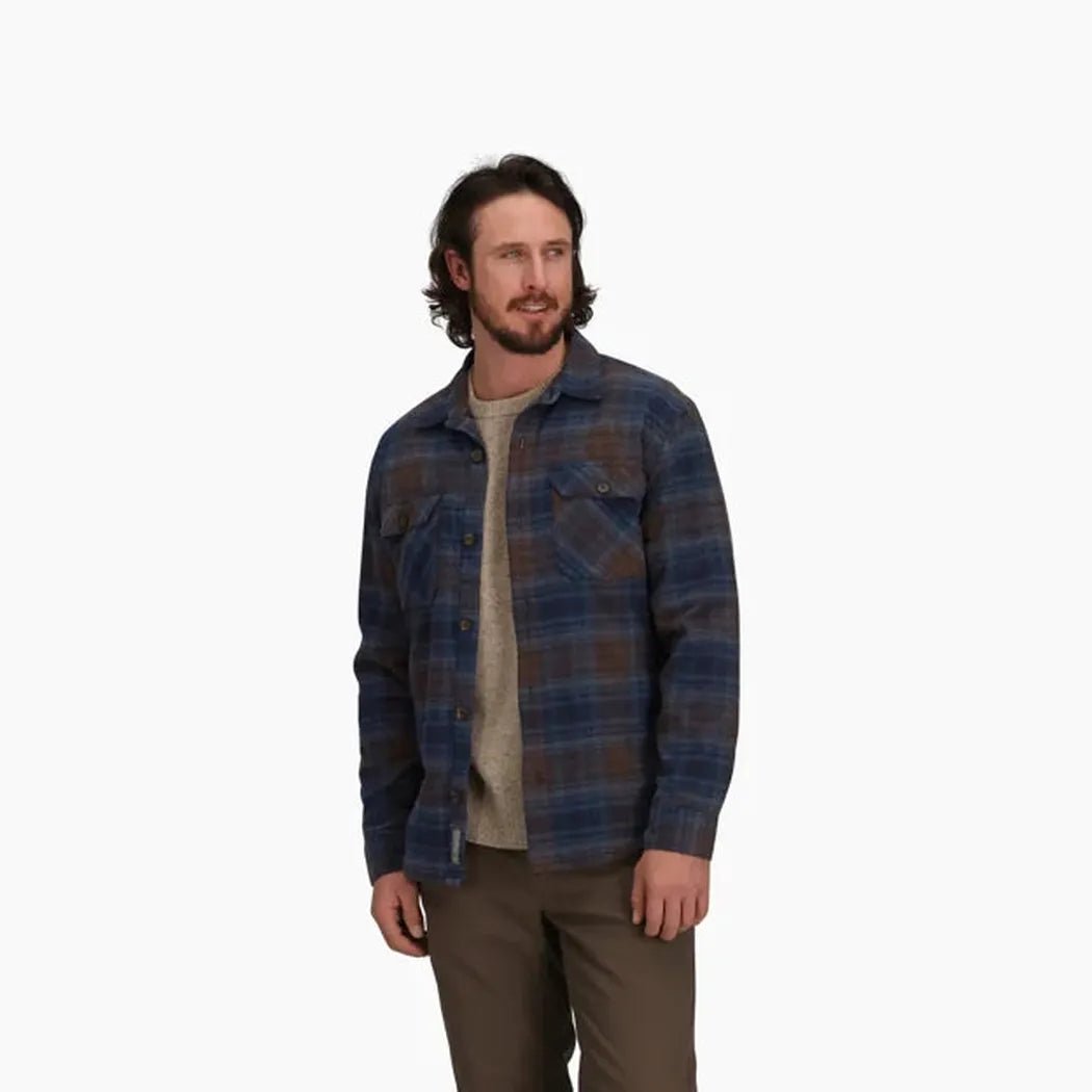 A man wearing the Royal Robbins Men's Snowcap Lined Flannel in Navy Tioga Pld stands against a plain white background.