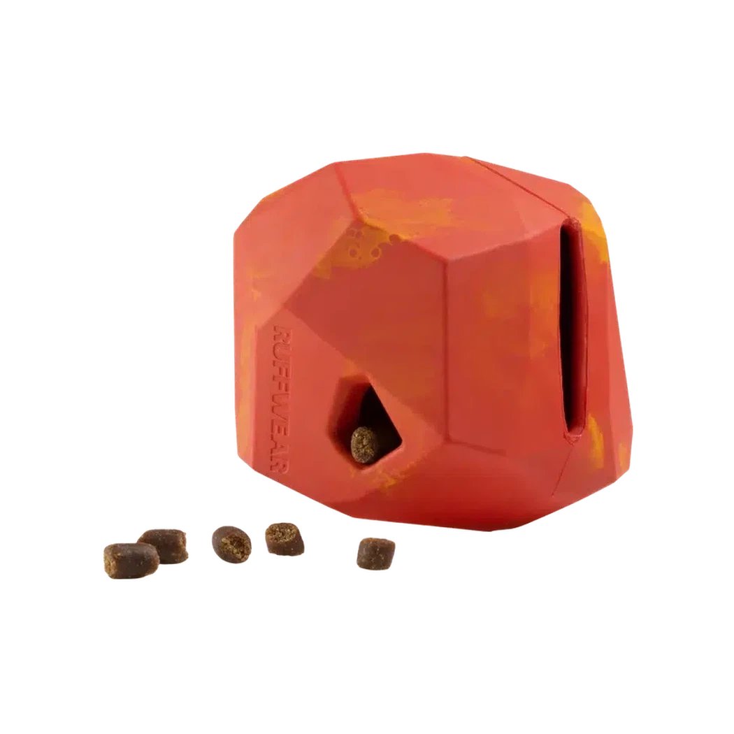 A front view of the Ruffwear Gnawt-a-rock in Dandelion Yellow showing the opening with a treat inside and a few treats on the white background.